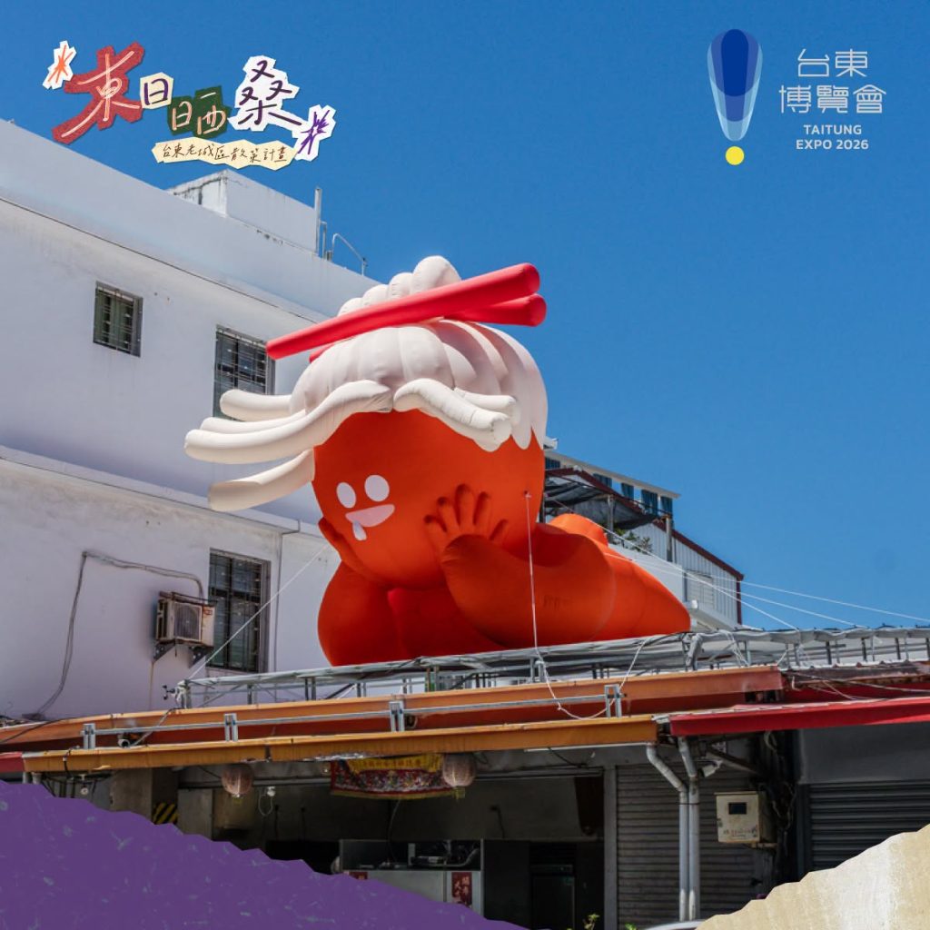 橘紅色晒桑旅人趴臥在寶桑路鐵皮屋簷上,捲曲髮型搶眼,姿態放鬆悠閒