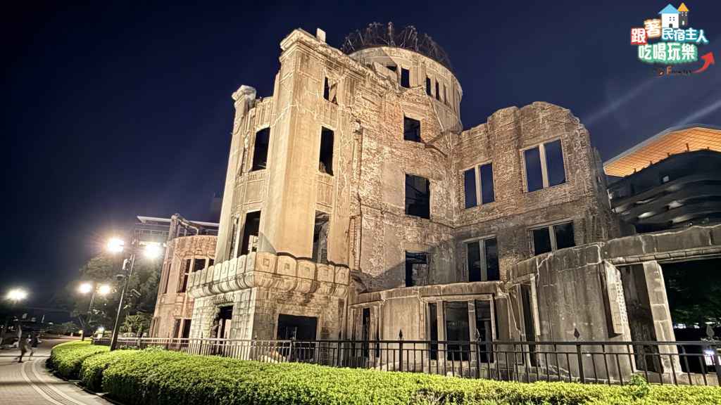 廣島原爆圓頂館夜間外觀,鋼架圓頂在燈光下清晰可見,斑駁磚牆與後方現代建築形成對比
