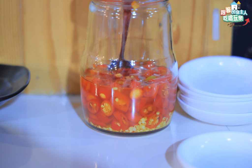 娜滋滋烤魚魯肉飯特寫,深褐色透亮滷汁搭配軟爛豬肉丁,旁附自製醃漬辣椒罐