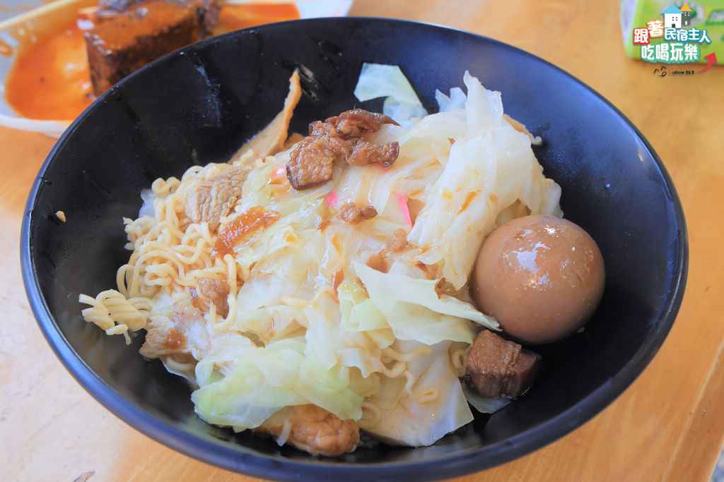 一碗鍋燒王子麵端上桌,碗裡鋪著高麗菜、肉片與一顆滷得發亮的滷蛋